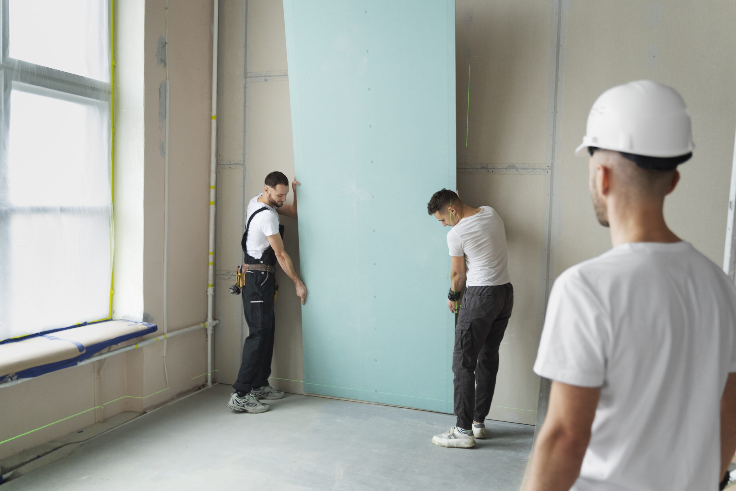 Profissional realizando a instalação de divisórias em drywall em um escritório moderno em Curitiba.